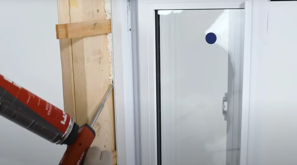 applying weatherproof sealant around window frame